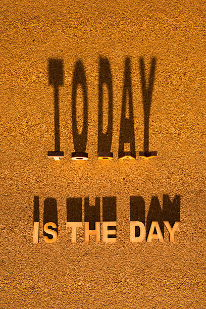 The wooden words TODAY IS THE DAY standing with shadow