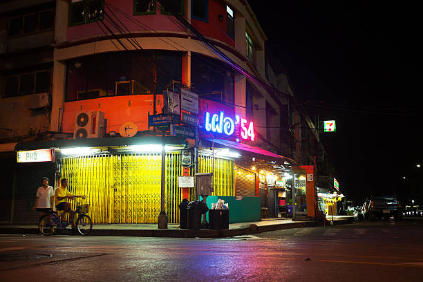 Bangkok, Thailand - November 1, 2014: Capture of a closed restaurant with neon lights at night. Scene is in street Chokchai 4 corner Soi 54. A young thia couple is in street, guy on bicycle. Late night shot.