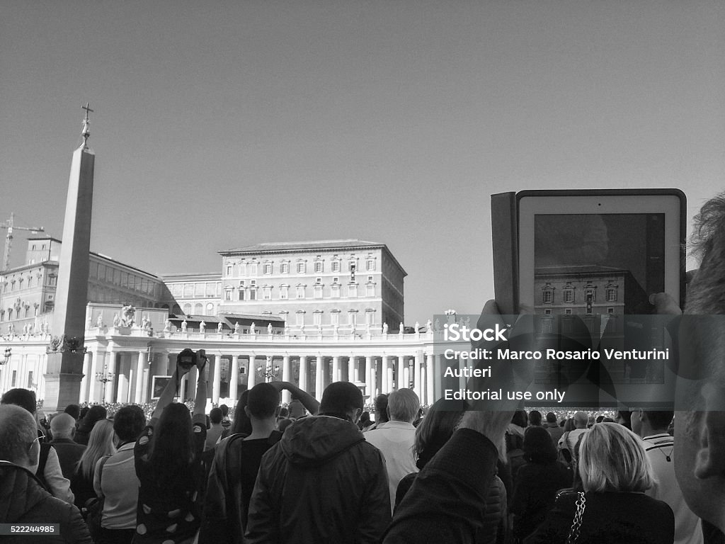 The Pope speaks while people film him with tablets Vatican City, Vatican - November 2, 2014: a usual crowd gathers in front of the Pope at midday on Sundays. The Pope is visible out of his balcony in the image captured by a man on his iPad's screen. Other people use digital devices to capture images of the event.  Vatican Stock Photo