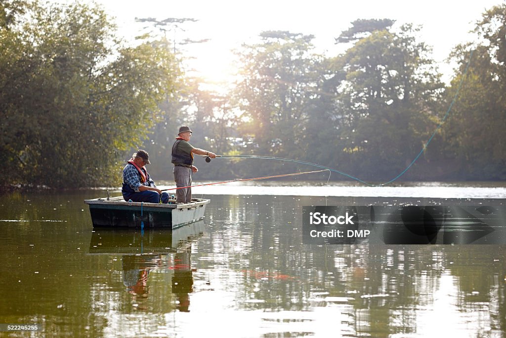 Two senior men in a boat fishing Two senior men in a boat fly fishing on a sunny day Fishing Stock Photo