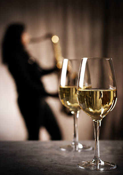 Wine & Jazz: Glasses of white with with saxophone player stock photo