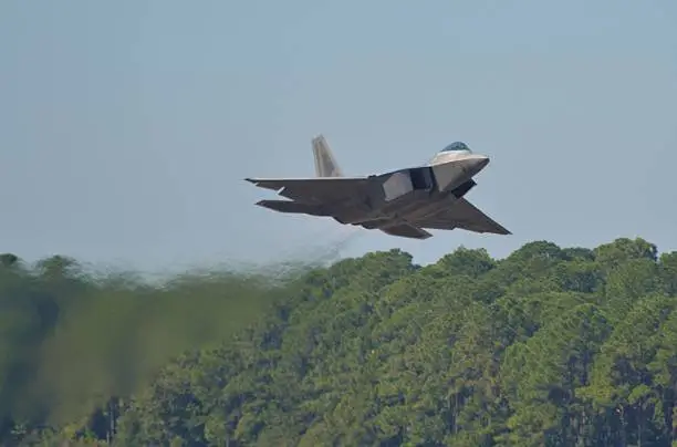 An F-22 fighter jet taking off using afterburner.