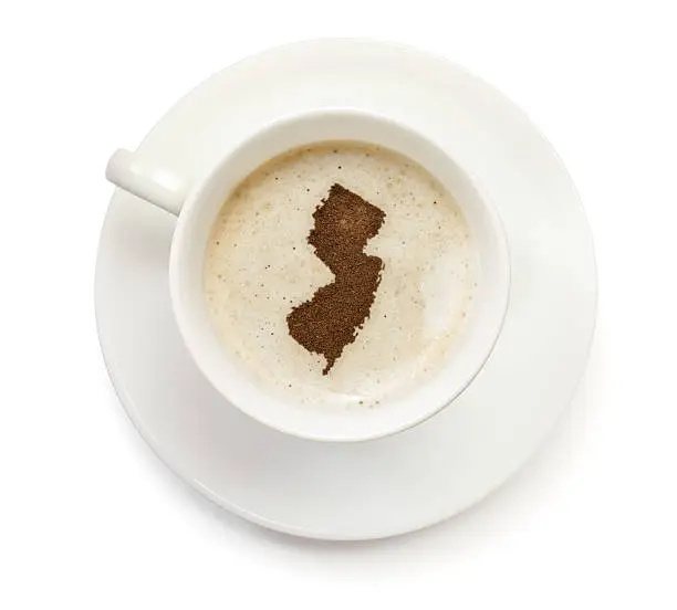 A top shot of a cup of coffee with froth and powder in the shape of New Jersey (USA).(series)   How about having a break :)