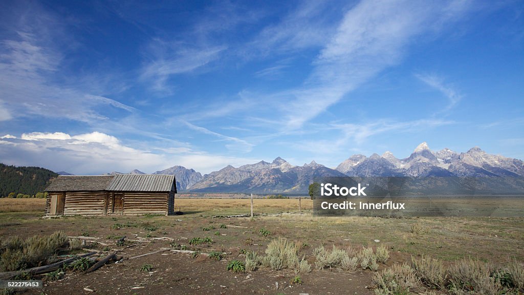 Old log cabin, Wyoming Teton mountain range with an old log cabin in the foreground. Wyoming summer day, blue sky, landscape.  Blue Stock Photo