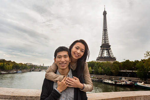 Young Asian couple on a romantic vacation in front of the Eiffel Tower in Paris