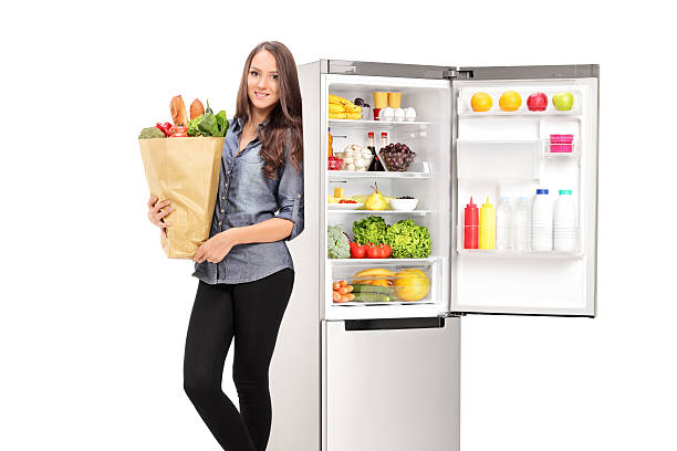 istock Woman holding a grocery bag by an open fridge 522292895