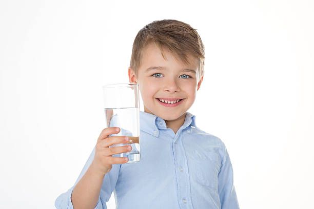 smiling boy with water kid holding a glass in his hand little boys blue eyes blond hair one person stock pictures, royalty-free photos & images