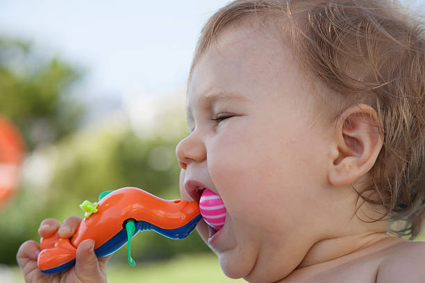 baby eating plastic toy stock photo