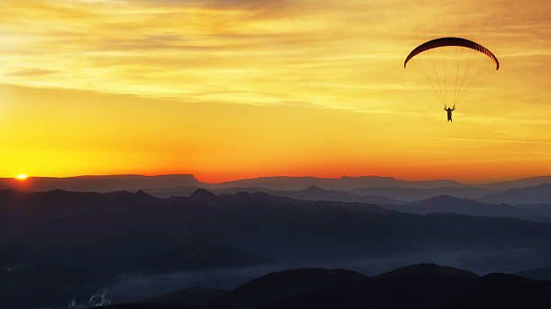 istock Paraglide silhouette over mountains at sunset 522302586