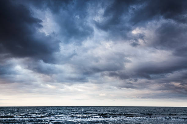 drammatico cielo nuvoloso scuro di pioggia sul mare - scuro foto e immagini stock