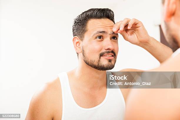 Man Plucking His Eyebrows In The Bathroom Stock Photo - Download Image Now - Eyebrow, Eyebrow Tweezers, 20-29 Years