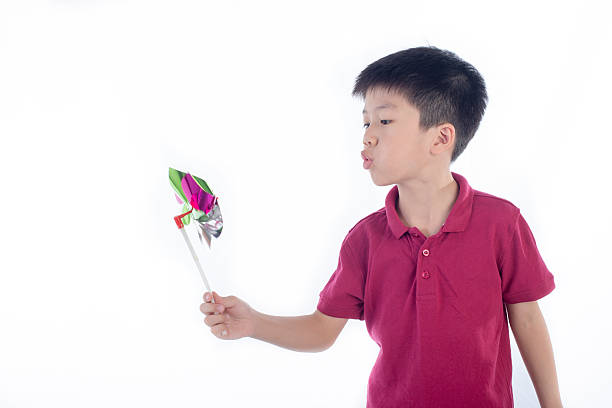 studio shot of a Chinese boy playing with pinwheel - isolated on white
