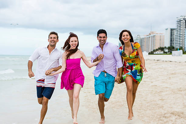 istock Smiling four people holding hands and running on the beach 522309830