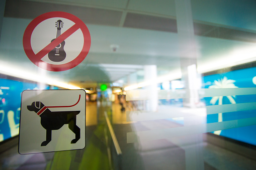No guitar and free dog allowed sign stickers on transparent doors at the entrance of a international airport