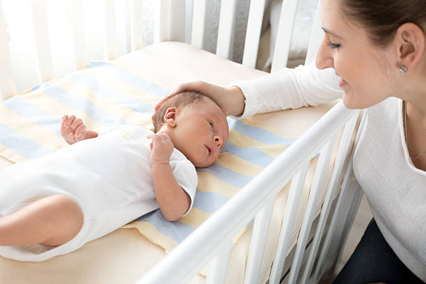 istock happy smiling mother caressing her baby lying in cot 522311212