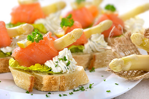Delicious canapes with German white asparagus, cream cheese with herbs, smoked salmon on Italian ciabatta bread with lettuce leaves