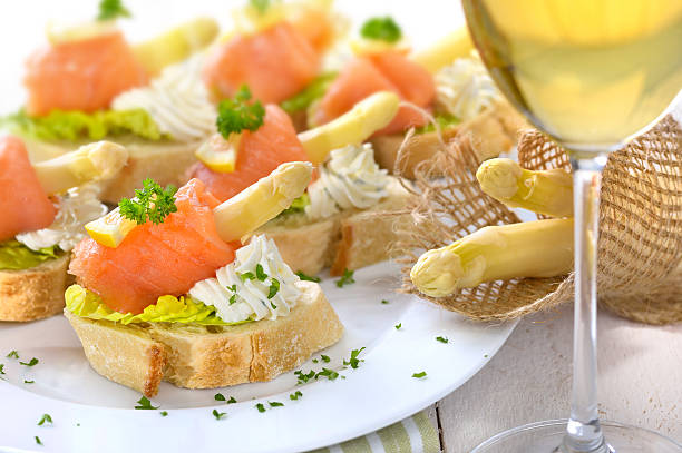 Delicious canapes with German white asparagus, cream cheese with herbs, smoked salmon on Italian ciabatta bread with lettuce leaves
