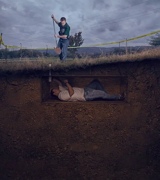 CSI officer has found the male victim buried alive and begins to dig with a shovel to save him.