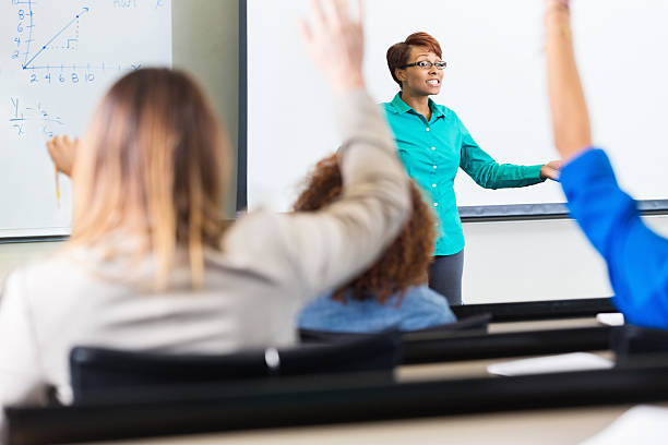 College or high school professor asking students to answer question Students raising hands to ask question in lecture hall classroom teenage high school girl raising hand during class stock pictures, royalty-free photos & images