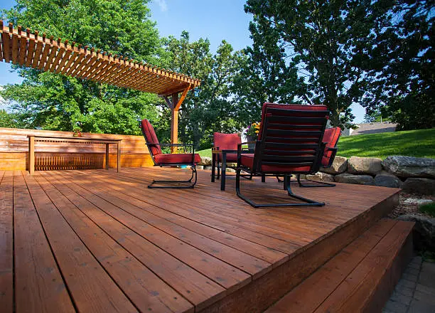 Backyard deck with deck chairs and a pergola on a sunny summer day.