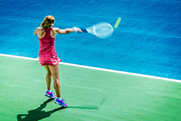Professional tennis player playing a game of tennis on a court. He is about to hit the ball with the racket. The ball is suspended in the air.