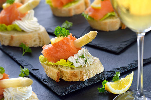 Delicious canapes with German white asparagus, cream cheese with herbs, smoked salmon on Italian ciabatta bread with lettuce leaves