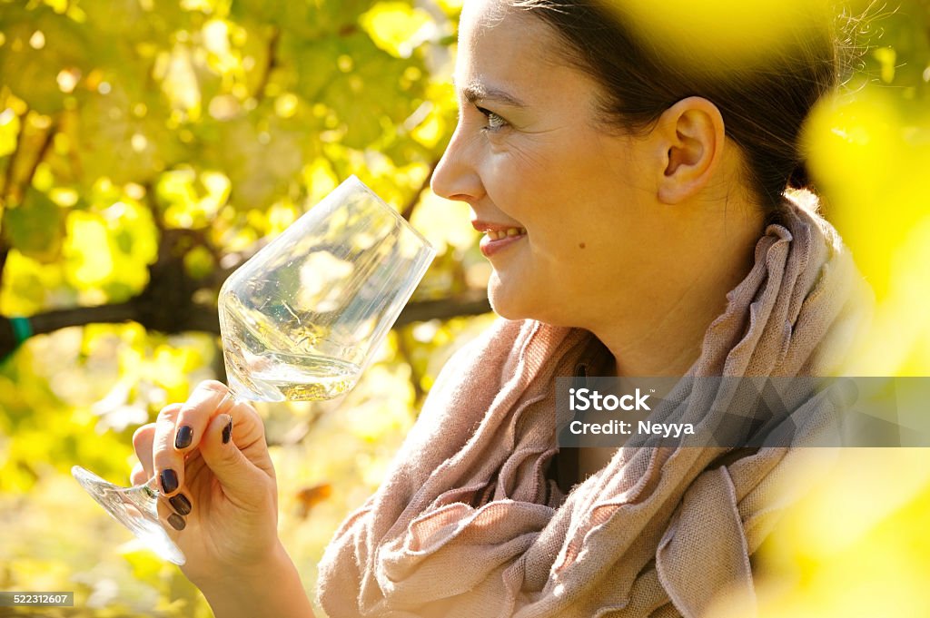 Female Winemaker with Glass of White Wine in Vineyard Female winemaker holding glass of white wine in vineyard. Selective focus, back lit. Goriška Brda, Slovenia, Europe. Adult Stock Photo