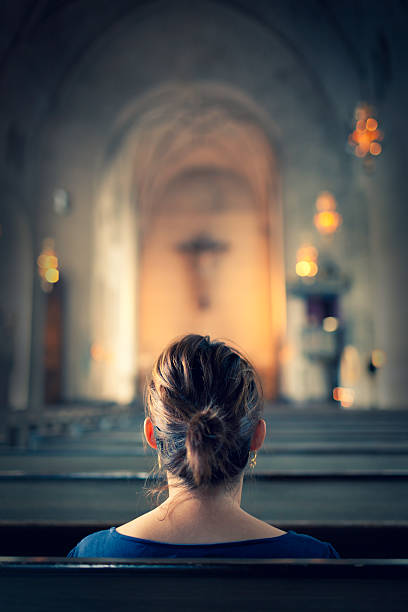 Woman visiting a christian church A woman sitting in a bench row in a large old christian church. church ladies stock pictures, royalty-free photos & images