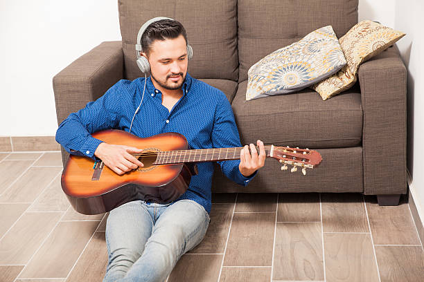 istock Guy with headphones playing the guitar at home 522313066
