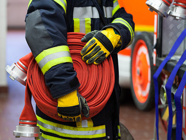 pompiere con il tubo flessibile arrotolato - vigile del fuoco foto e immagini stock