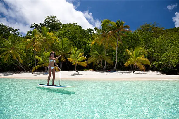 sexi woman in white bikini paddling on stand up paddle board close by Salomon Bay, St.John, US Virgin Islands