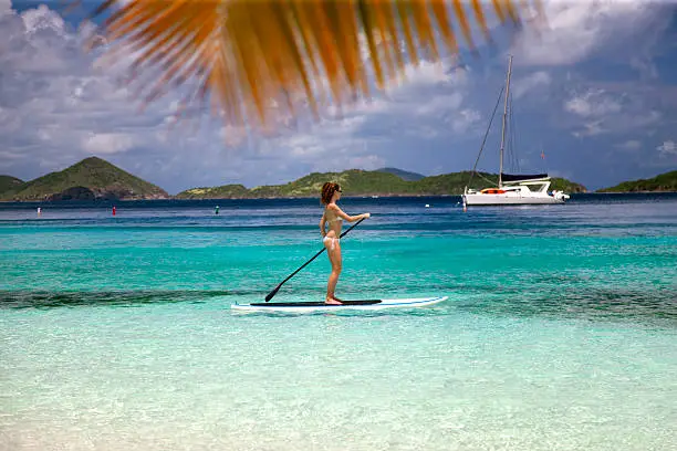 sexi woman in white bikini paddling on stand up paddle board by Salomon Bay Beach, St.John, US Virgin Islands