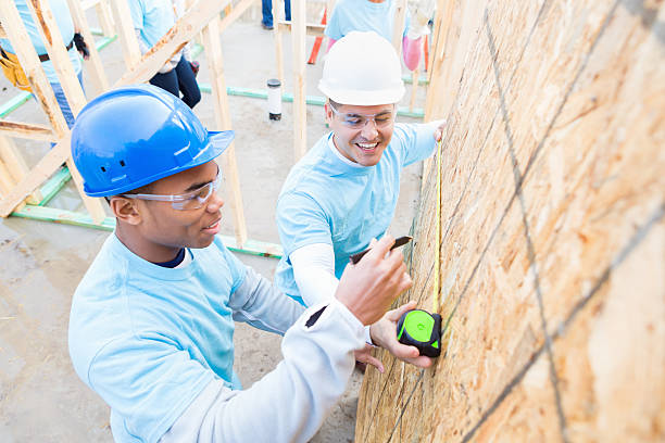 istock Young man measures wall at charity home worksite 522314644