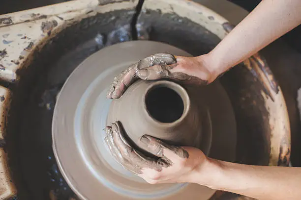 Human hands working on pottery wheel, close up