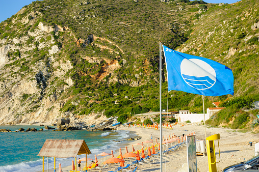 Kefalonia, Greece - September 16, 2014: Blue flag on Petani beach, a symbol of ecological beaches at the seaside in Europe. Blue flag on the beach for the awareness