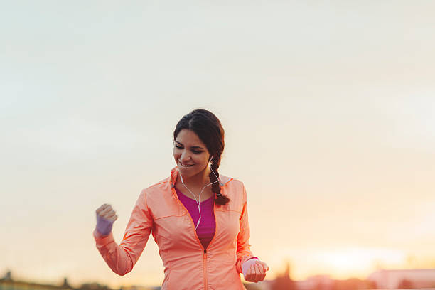 I Did It! Female Runner Jogging in the city and finishing her training with her hand up in the air screaming with happiness. She made her goal! potential energy stock pictures, royalty-free photos & images