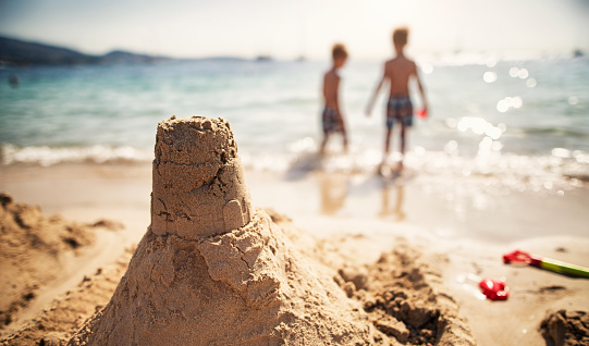 Two little brothers have just built a sandcastle. Sunny summer day.
