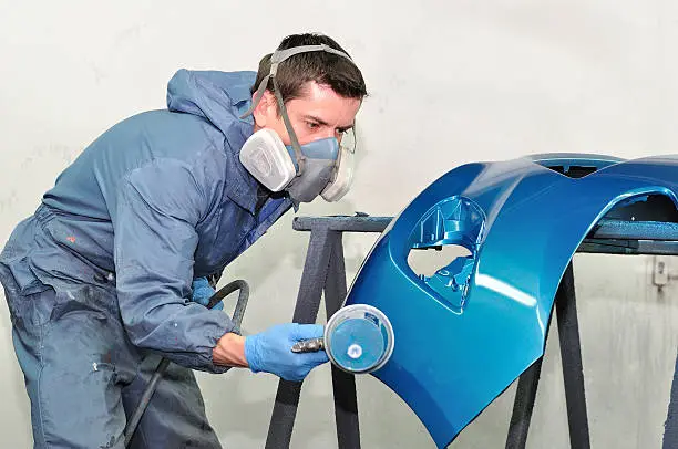 Photo of Worker painting blue bumper.