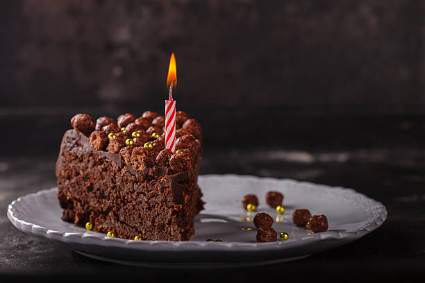 istock Piece of chocolate cake with candle on a dark background 522326358