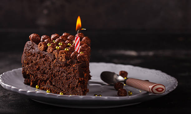 istock Piece of chocolate cake with candle on a dark background 522326398