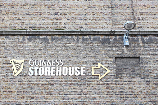 Old stone facade with Guinness Storehouse logo showing the way to that tourist attraction. Photo taken in Dublin, Republic of Ireland on June 15, 2014.