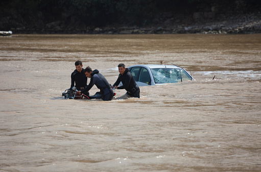 Olympos, Turkey - October 14, 2009: Frogmen recovering motorcycle near sunken car in Mediterranean Sea in Olympos, Turkey. Olympos, a famous holiday spot in Antalyas Kumluca district, was hit by floods. The floods swept away about 50 cars from the road into the sea.
