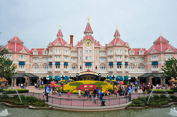 Paris, France - August 14, 2012: Image of the entrance in Disneyland Park from Paris. Tourists get into the park in morning, some take photo with the flowers.