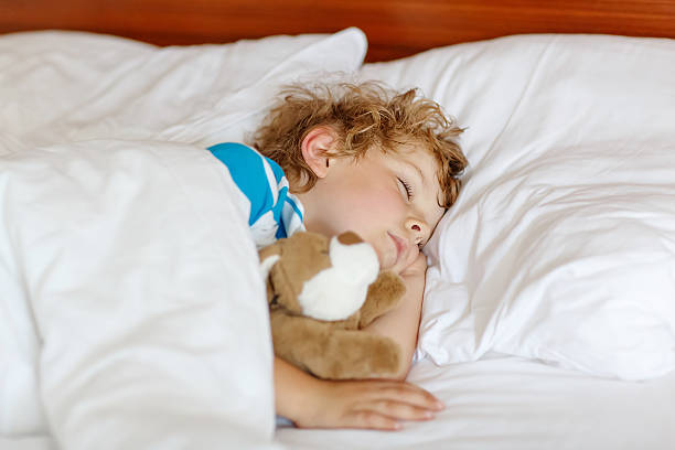 istock Adorable kid boy after sleeping in white bed with toy 522332857
