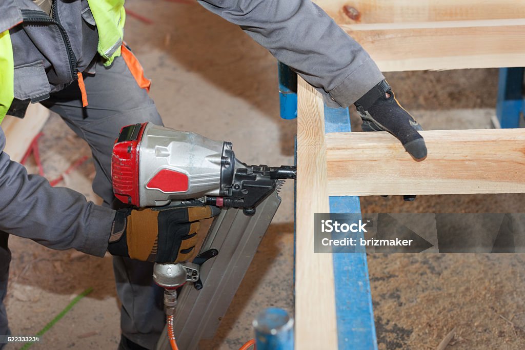 Worker use Framing Nailer to attach wooden beams Building a wall for frame house.Worker use Framing Nailer to attach wooden beams Adult Stock Photo