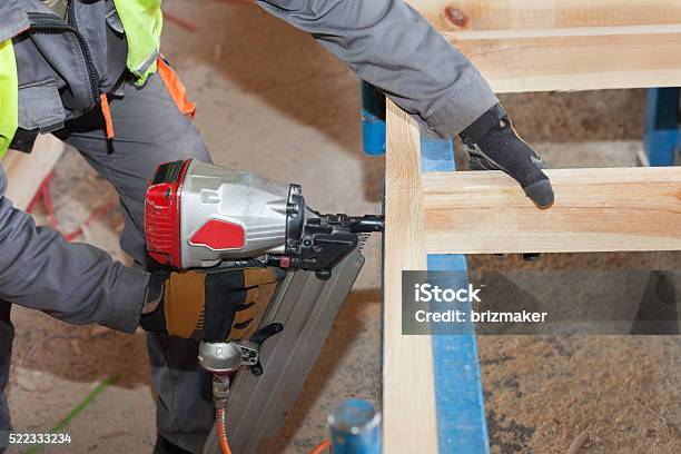 Worker Use Framing Nailer To Attach Wooden Beams Stock Photo - Download Image Now - Adult, Attached, Building - Activity