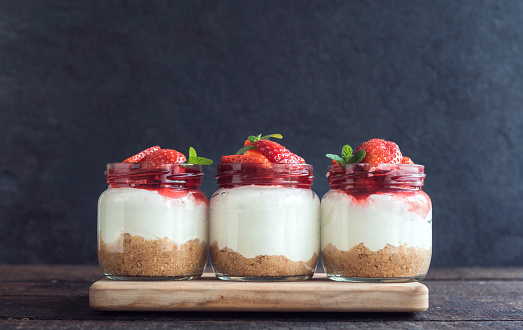 Sweet homemade cheesecake with strawberries in the jar on wooden background,selective focus