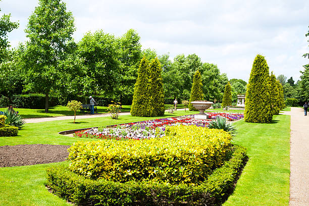 London, United Kingdom - June 16, 2012: Flower beds, trees and hedges of Regent's Park in summer. In center is flower bed in scape of Union Jack. Some people and tourists are in park.