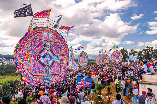 Santiago Sacatepequez, Guatemala - November 1, 2010: Giant kites in crowded cemetery depicting religious & Mayan images. Locals display huge circular kites called barriletes & fly smaller ones each year in the cemetery on All Saints' Day to honor spirits of the dead.