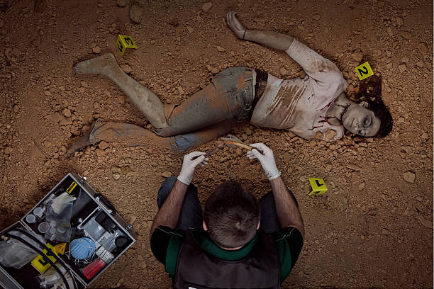 CSI officer gathering evidence female victim CSI officer gathering evidence at the scene of a buried female victim. Body is decomposed and has a cut throat. He is holding the murder weapon; a straight razor. victim photos stock pictures, royalty-free photos & images